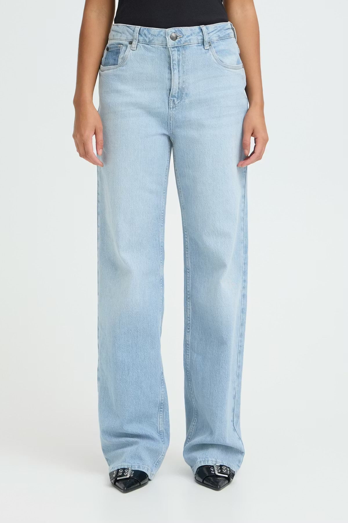 Light blue jeans worn by a person on a white background perfect for sneakers